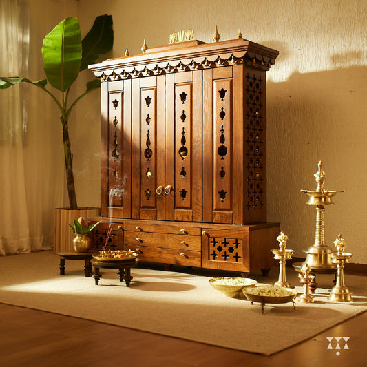 A solid wood mandir with doors, pure brass bells, accessories, cutwork designs and storage, tinted in an almond brown color