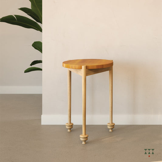 Wooden side table against a plain wall with a plant in the corner