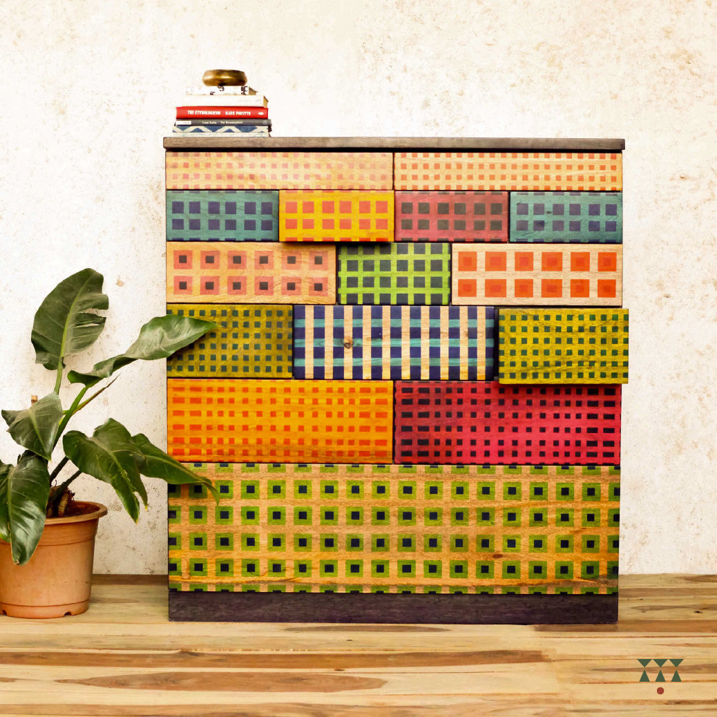Colorful madras check inspired patterned chest of drawers with a plant on a wooden floor.