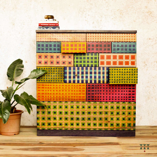 Colorful madras check inspired patterned chest of drawers with a plant on a wooden floor.