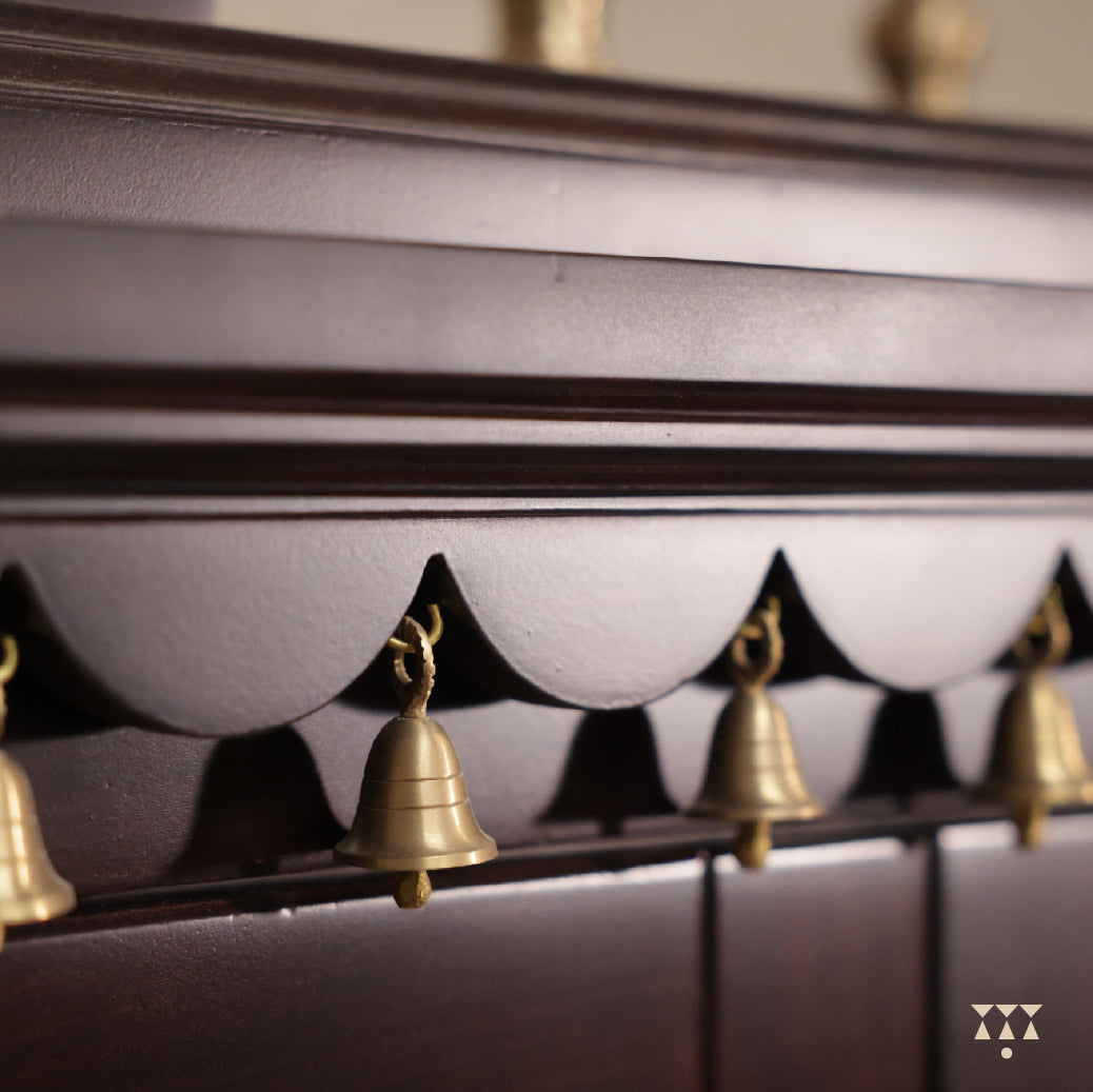 Close up of top wood panel of Vignaharta temple with decorative golden bells.