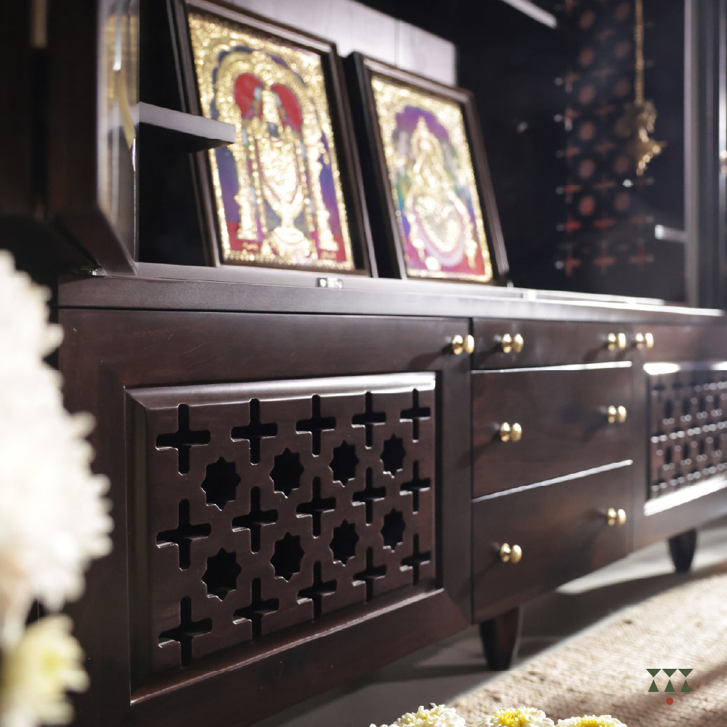 Close up of Vignaharta Temple bottom wooden sideboard with decorative carvings and two framed artworks on a shelf.