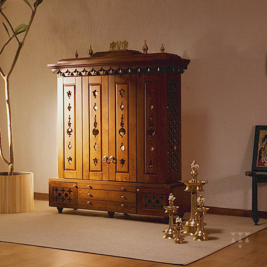 A solid wood mandir with doors, pure brass bells, accessories, cutwork designs and storage, tinted in an almond brown color